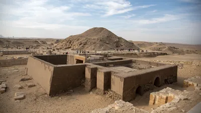 Saqqara, Egypt - Feb 5, 2024: Ancient Egyptian mastaba tomb in Saqqara Necropolis with the Pyramid of Unas visible in the background.